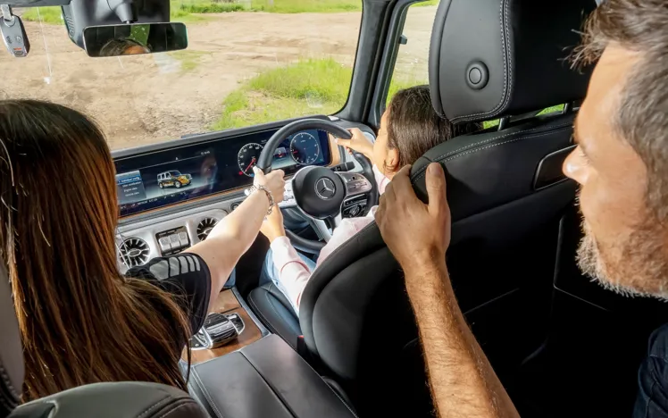 Young driver navigating a 4x4 vehicle over rugged terrain at Mercedes-Benz World's off-road course during a one-hour session.