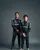 Two Mercedes-AMG Petronas Formula One drivers in full race suits posing against a dark studio background, smiling confidently with arms relaxed.