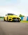 Bright yellow Mercedes-AMG sports car speeding down the track at Mercedes-Benz World, showcasing sleek design and high-performance engineering.