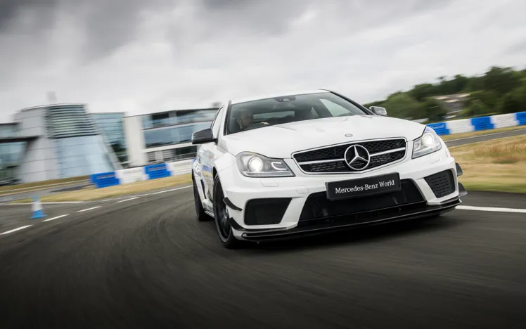 Mercedes-AMG vehicle drifting on a wet track, creating dramatic spray as it powers through a curve during a performance driving experience.