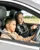 Young boy driving a car with a female instructor beside him, guiding and pointing ahead during a junior driving experience on a track.